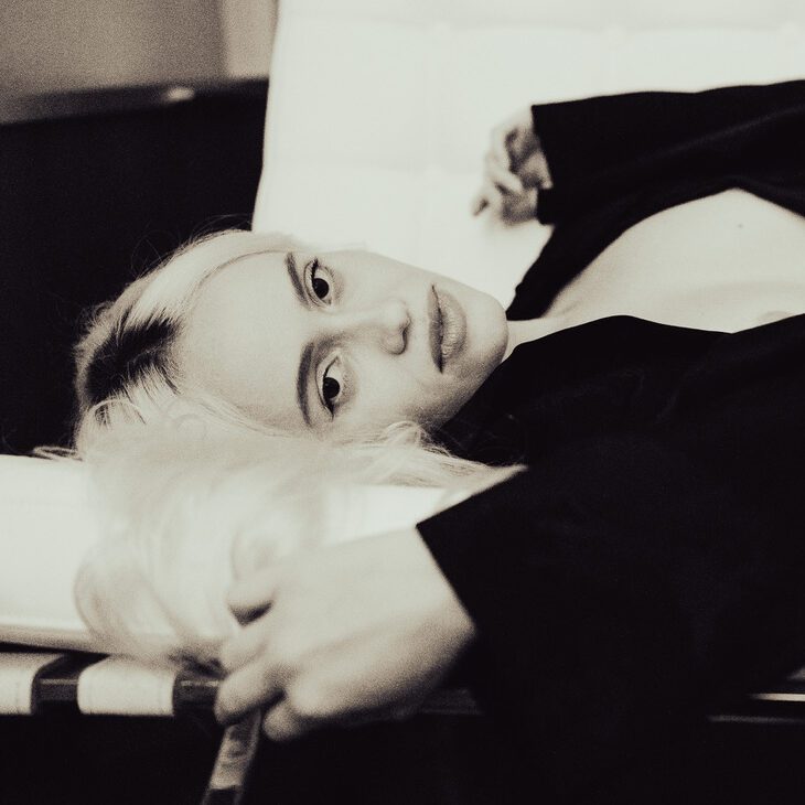 Woman lying on a couch looking toward the camera